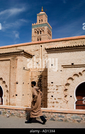 Uomo marocchino indossa djellaba, camminando lungo il bordo del Parc Lalla Hasna, con la moschea di Koutoubia in background, a Marrakech, Marocco. Foto Stock