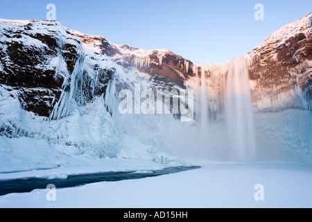L'Islanda, Skogar, Skogafoss, Skogafoss cascata circondata da neve e ghiaccio in inverno Foto Stock