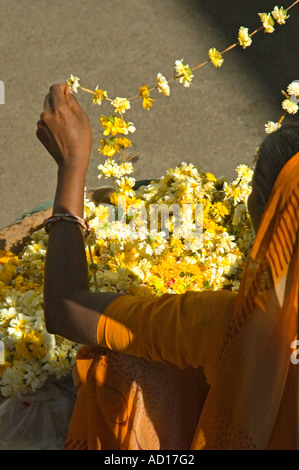 Verticale di vista in elevazione di una donna Indiana vendita giallo religiosa ghirlande di fiori in Udaipur Foto Stock