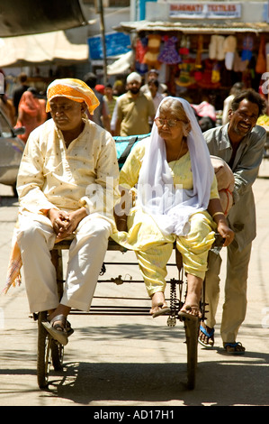 Ritratto verticale di un anziano Indian giovane lift sul retro del carrello essendo spinto in giù la strada in Pushkar Foto Stock