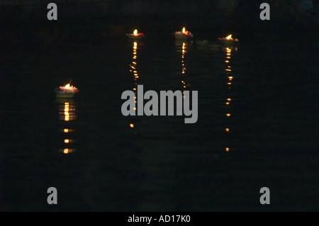 Orizzontale vista notturna di quattro piccoli religiosi 'diyas' candele galleggianti lungo il fiume Gange a Varanasi Foto Stock