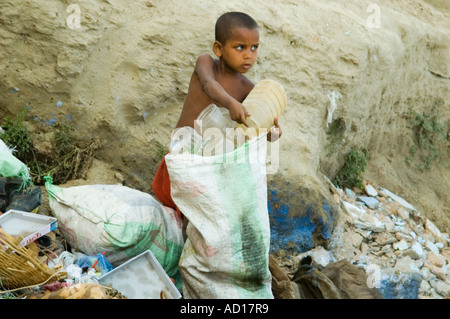 Ritratto orizzontale di un povero ragazzo la raccolta di contenitori di plastica su un mucchio di rifiuti per il riciclo. Foto Stock