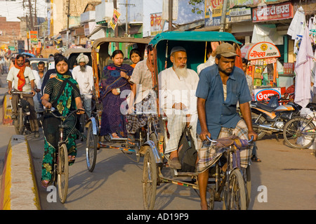 Una compressa di vista in prospettiva di una strada trafficata in Varanasi con persone in risciò ciclo e biciclette. Foto Stock