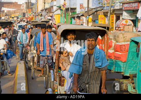 Una compressa di vista in prospettiva di una strada trafficata in Varanasi con persone in risciò ciclo e biciclette. Foto Stock
