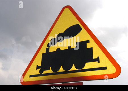 Cartello stradale per locomotive a vapore con fumo su un cartello triangolare giallo e rosso contro un cielo nuvoloso in Polonia. Foto Stock