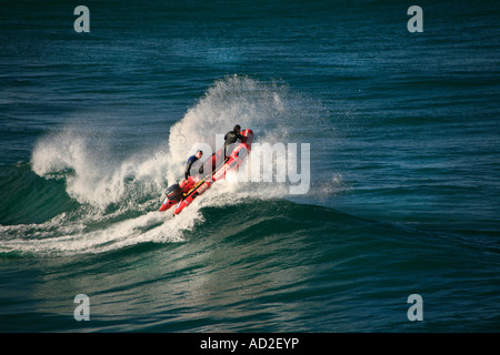 La vita dei risparmiatori in un powered surf barca di salvataggio sormontano un oceano onda al largo delle coste australiane Foto Stock