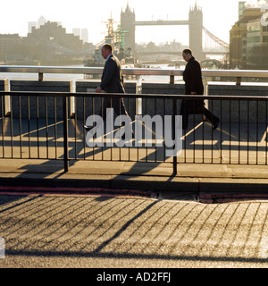 Andare al lavoro la mattina presto a chi lavora in ufficio camminando sul Ponte di Londra Foto Stock