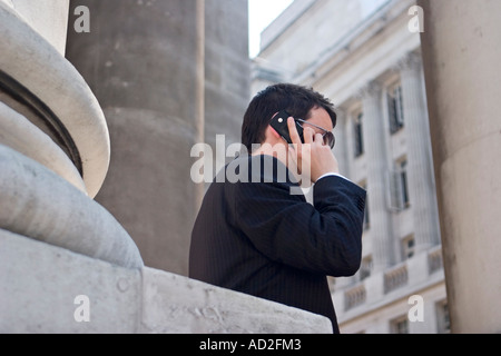 Giovane imprenditore utilizza il telefono cellulare nella città di Londra al di fuori del Royal Exchange Foto Stock