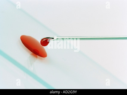 Siringa ponendo un campione di sangue in una diapositiva, angolata. Foto Stock