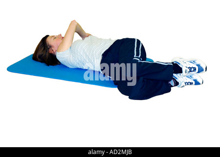 Lone femmina adulta di eseguire esercizi di stretching su un tappetino set contro uno sfondo bianco Foto Stock