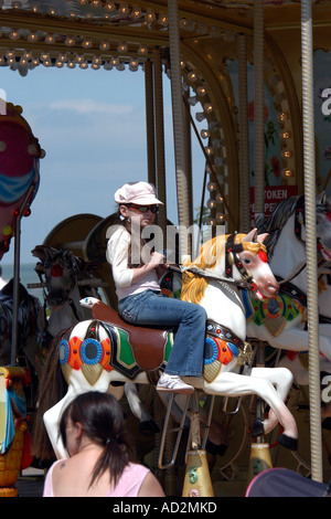 Giovane ragazza adolescente indossando vestiti alla moda a cavallo di una giostra cavallo Foto Stock