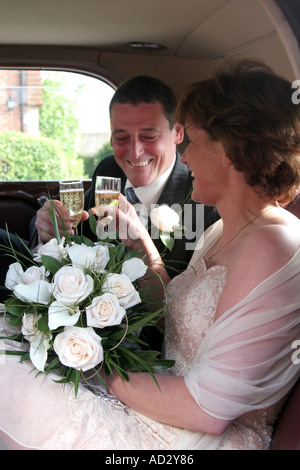 Appena una coppia sposata a celebrare in auto con champagne Foto Stock