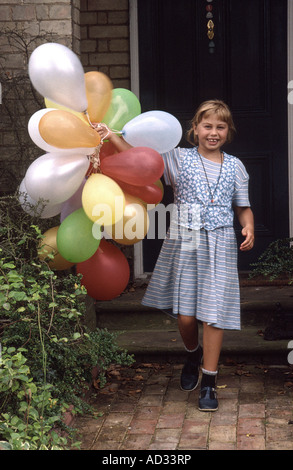 8 anno vecchia ragazza che trasportano palloncini per una festa di compleanno. Foto Stock