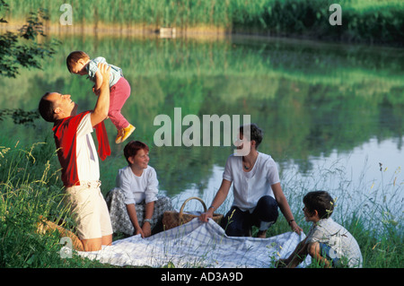 Famiglia di cinque avente pic-nic nei pressi del lago piccolo in Baviera, Germania Foto Stock