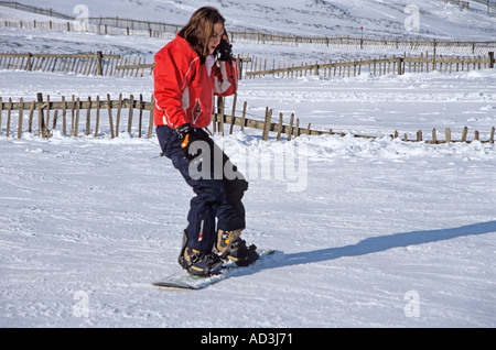 MORAY SCOZIA Regno Unito febbraio ragazza in una giacca rossa snowboard su una delle piste del popolare Scottish Lecht Ski Centre buone condizioni di neve Foto Stock