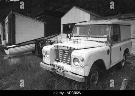 Picchiati Land Rover parcheggiato a capannoni sulla spiaggia di Morfa Nefyn, Lleyn Peninsula, il Galles del Nord Foto Stock