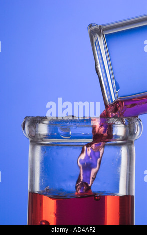 Rosso fluido che viene versata dal tubo di prova nella beuta di Erlenmeyer Foto Stock