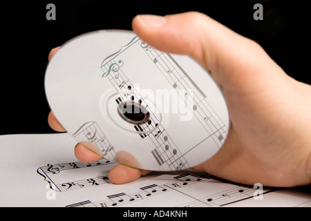 Un uomo in possesso di un CD audio al di sopra di spartiti di musica Foto Stock