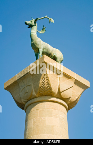 Vista verticale del buck/Stag Cervo statua su un alta colonna all'entrata del porto di Mandraki contro un cielo blu. Foto Stock