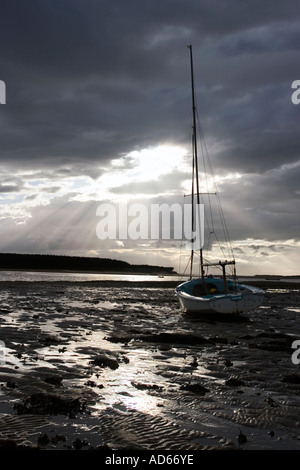 Barca sul fiume Findhorn estuario velme a Findhorn bay a bassa marea con un tempestoso cielo nuvoloso scuro dello sfondo. Moray, Scozia Foto Stock