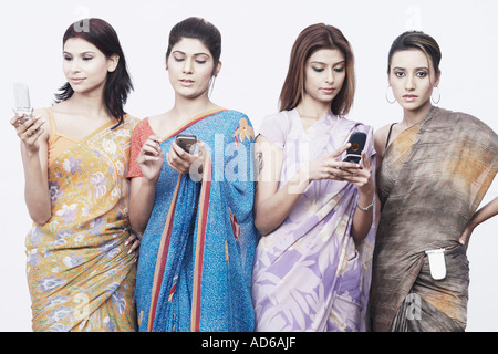 Close-up di quattro giovani donne tenendo i telefoni cellulari Foto Stock