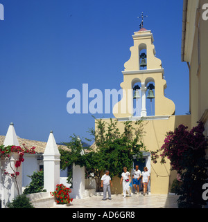 Il cortile e la torre campanaria del monastero del XIII secolo con fiori di arrampicata vitigni e quattro persone Paleokastritsa Corfu Grecia Foto Stock