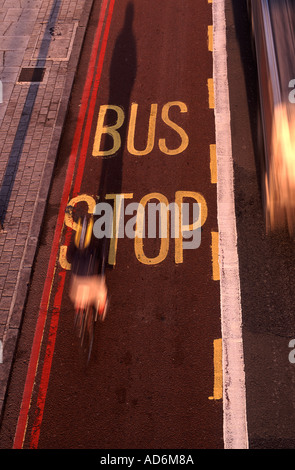 Fermata bus cycle lane con ciclista e passaggio di autobus in movimento sfocate nel tardo pomeriggio di luce, South Bank di Londra, Inghilterra Foto Stock