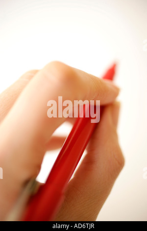 Mano che tiene la penna rossa in bilico per la scrittura Foto Stock