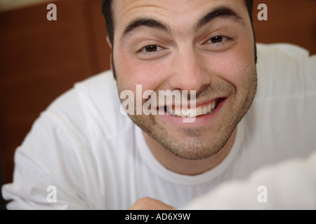 Ritratto di giovane uomo disteso sulla sua pancia e sorridente Foto Stock