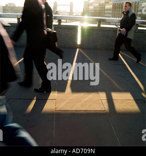Andare al lavoro la mattina presto a chi lavora in ufficio camminando sul Ponte di Londra Foto Stock