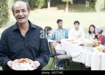Ritratto di un uomo anziano tenendo una torta Foto Stock