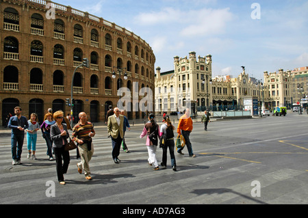 Le persone che attraversano la strada sulle strisce pedonali davanti a una corrida arena e alla stazione ferroviaria principale, Valencia, Spagna Foto Stock