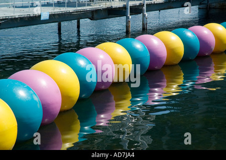 Grandi variopinte palline galleggianti formando una barriera attorno a un'area di gioco in un parco divertimenti sull'acqua Foto Stock