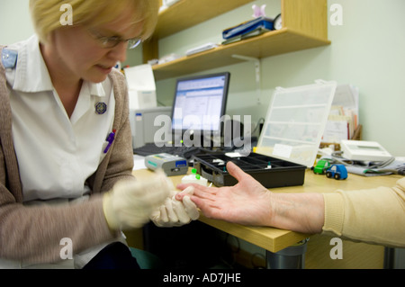 L'infermiera di prendere un campione di sangue dal dito del paziente Foto Stock