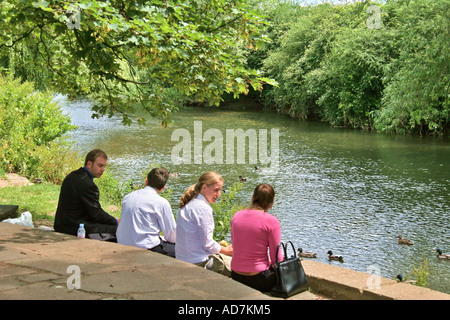 Gli amici sorseggiando picnic sulle rive del fiume Foto Stock
