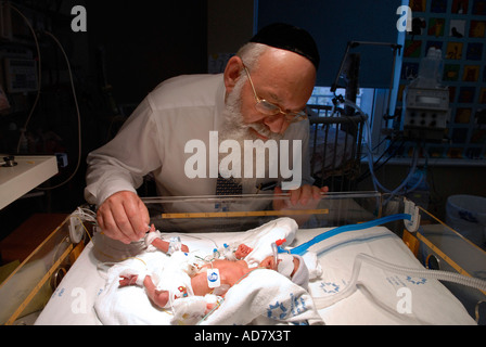 Un medico Haredi che controlla il neonato prematuro in un incubatore presso l'unità di terapia intensiva neonatale del Centro medico Share Zedek di Gerusalemme ovest Israele Foto Stock