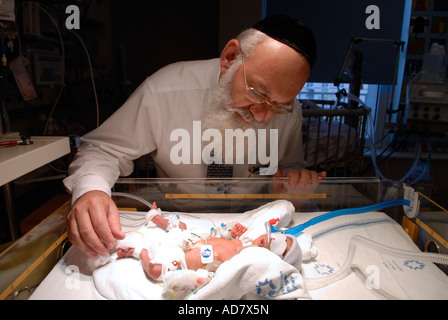 Un medico Haredi che controlla il neonato prematuro in un incubatore presso l'unità di terapia intensiva neonatale del Centro medico Share Zedek di Gerusalemme ovest Israele Foto Stock