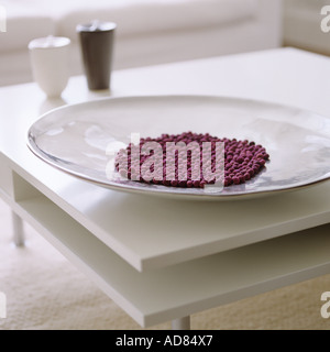 Essiccato viola i fagioli in un piatto bianco su bianco tabella di caffè Foto Stock