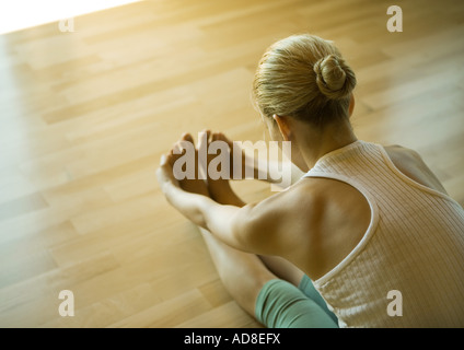 Donna seduto facendo piegare in avanti Foto Stock