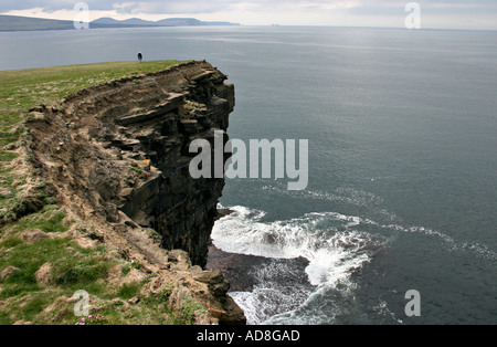 Una donna sta solo su Downpatrick Head. Mare Bianco breakers crash al di sotto di Foto Stock