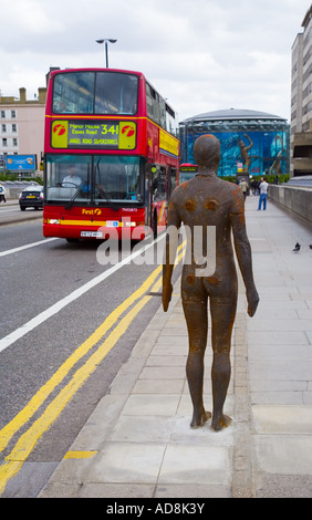 Antony Gormley scultura aspettando apparentemente un rosso London bus sul ponte di Waterloo Foto Stock