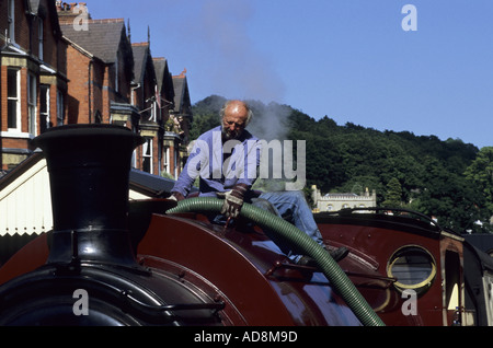 Uomo di riempimento locomotiva a vapore "Jessie' con acqua, stazione di Llangollen, Denbighshire, Wales, Regno Unito Foto Stock