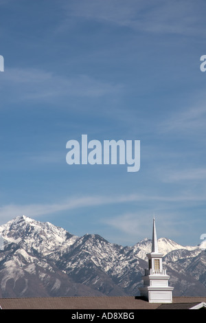 Una chiesa bianca steeple nella Salt Lake Valley, Utah, Stati Uniti d'America, con la coperta di neve montagne rocciose in background. Foto Stock