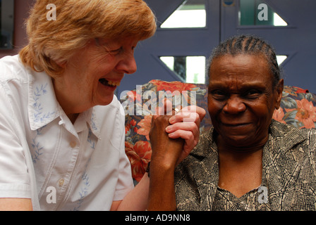 Membro del personale di assistenza presso la casa di cura per le persone con demenza scherzo di condivisione con residenti etnici, Londra, Regno Unito. Foto Stock