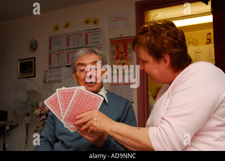 Membro del personale di assistenza a giocare a carte con gli anziani residente presso la casa di cura per i malati di demenza, Londra, Regno Unito. Foto Stock