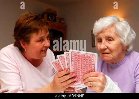Membro del personale di assistenza a giocare a carte con gli anziani residente presso la casa di cura per i malati di demenza, Londra, Regno Unito. Foto Stock