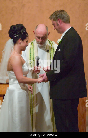 Il sacerdote pone l'anello sullo sposo s dito formale a nozze cattoliche in Irvine California Foto Stock