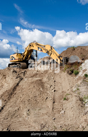 Scavatore giallo Caterpillar (CAT) sulla cima di un tumulo di sabbia contro cielo blu , Finlandia Foto Stock