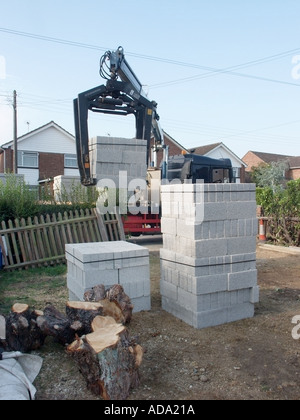 Scarico meccanico autocarro carico di blocchi isolanti sollevato dal pallet sul cantiere utilizzando gru meccanica Essex Inghilterra UK Foto Stock