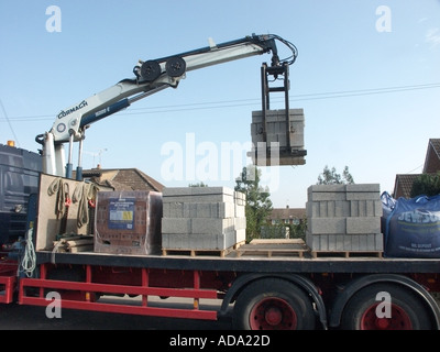 Scarico meccanico camion Jewson di carico di blocchi isolanti sollevato dal pallet sul cantiere utilizzando gru Essex Inghilterra UK Foto Stock